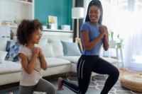 mother and young daughter doing lunges in their living room